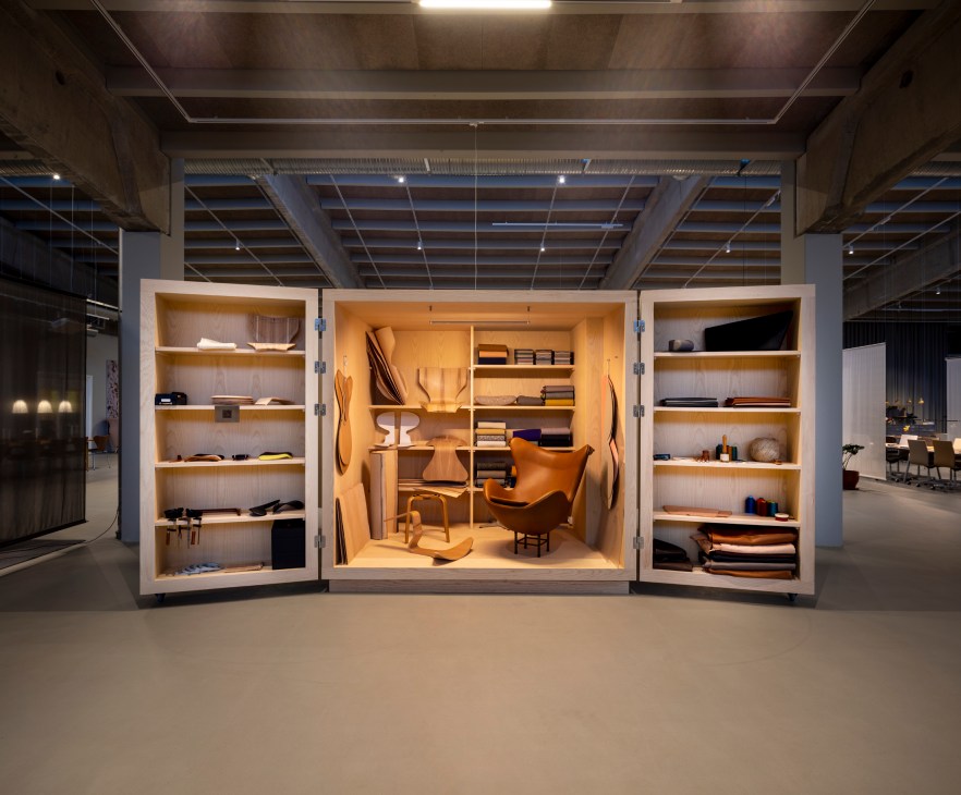 Wooden furniture display in illuminated cabinet with plywood chairs and archive pieces at Fritz Hansen Design Hall