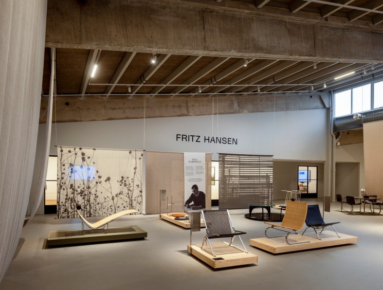 Modern chair designs displayed on wooden platforms in Fritz Hansen's Design Hall exhibition space