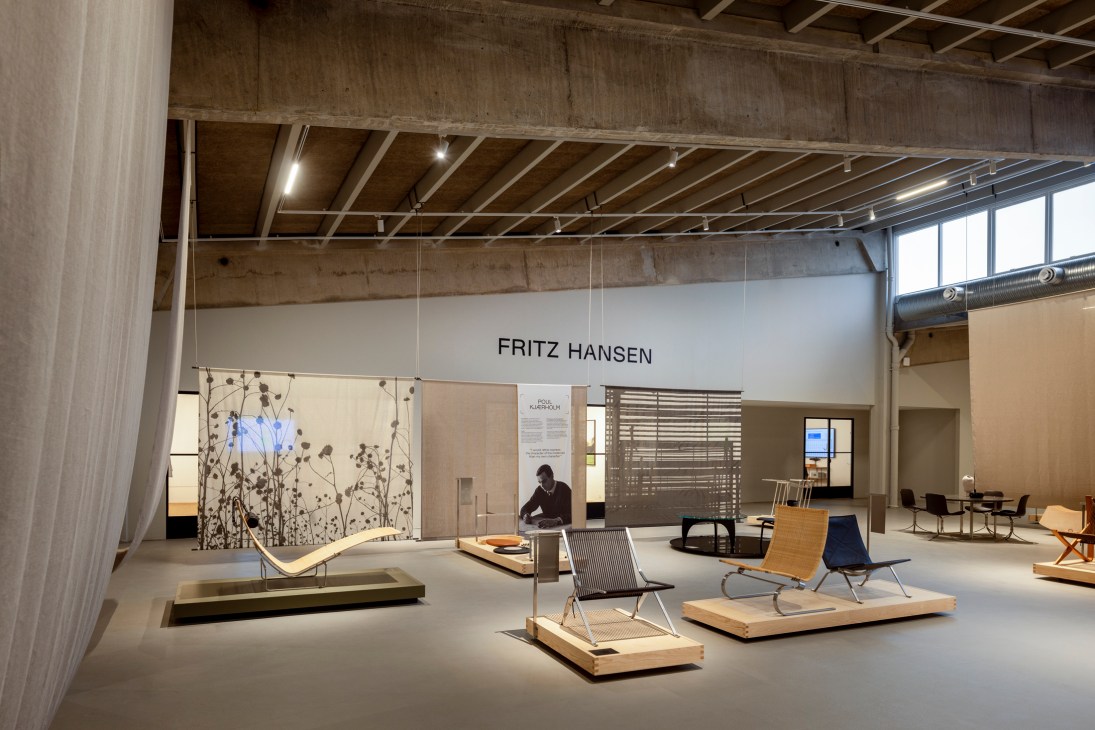 Modern chair designs displayed on wooden platforms in Fritz Hansen's Design Hall exhibition space