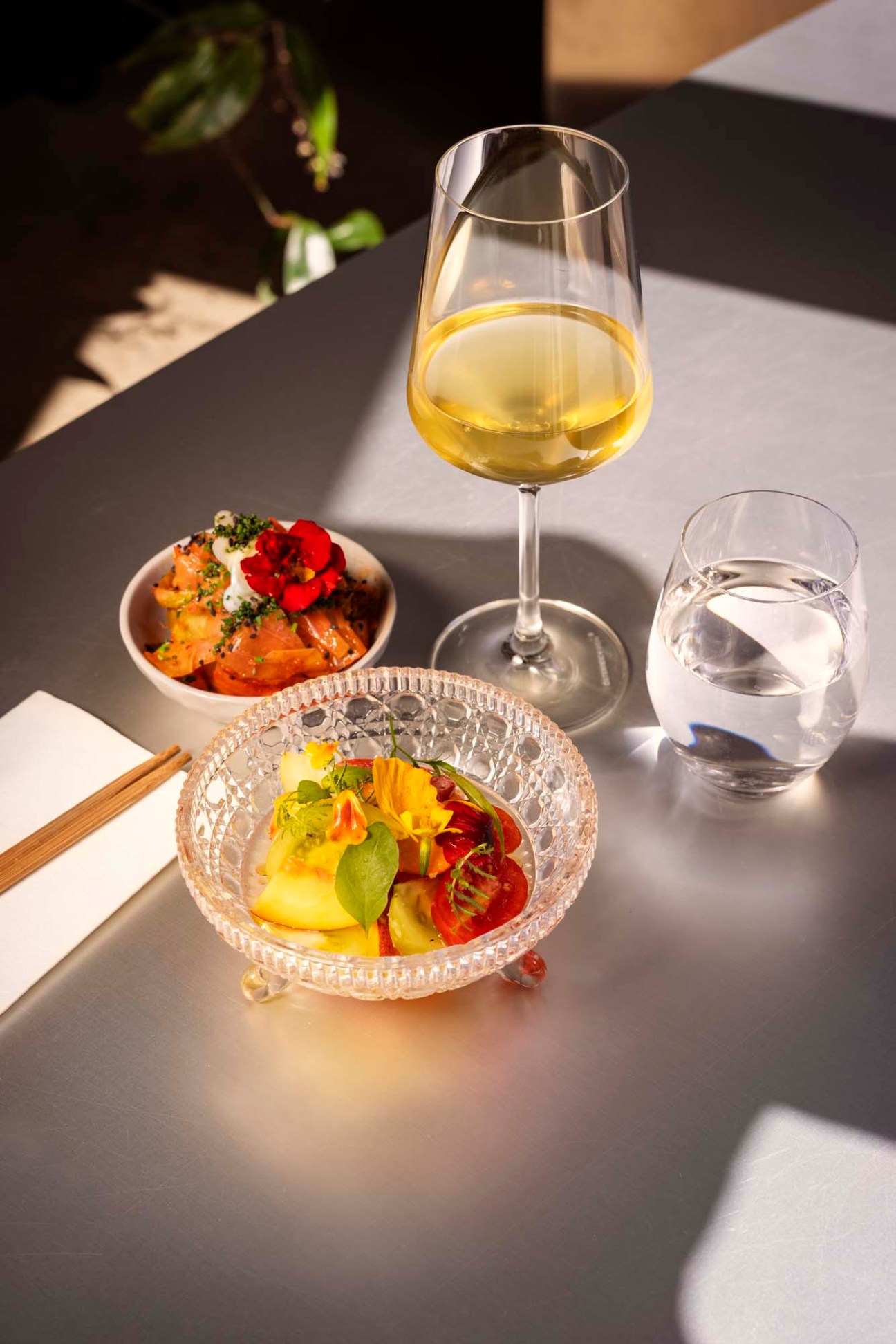 Elegant plated dishes with white wine and water at fine dining restaurant table.