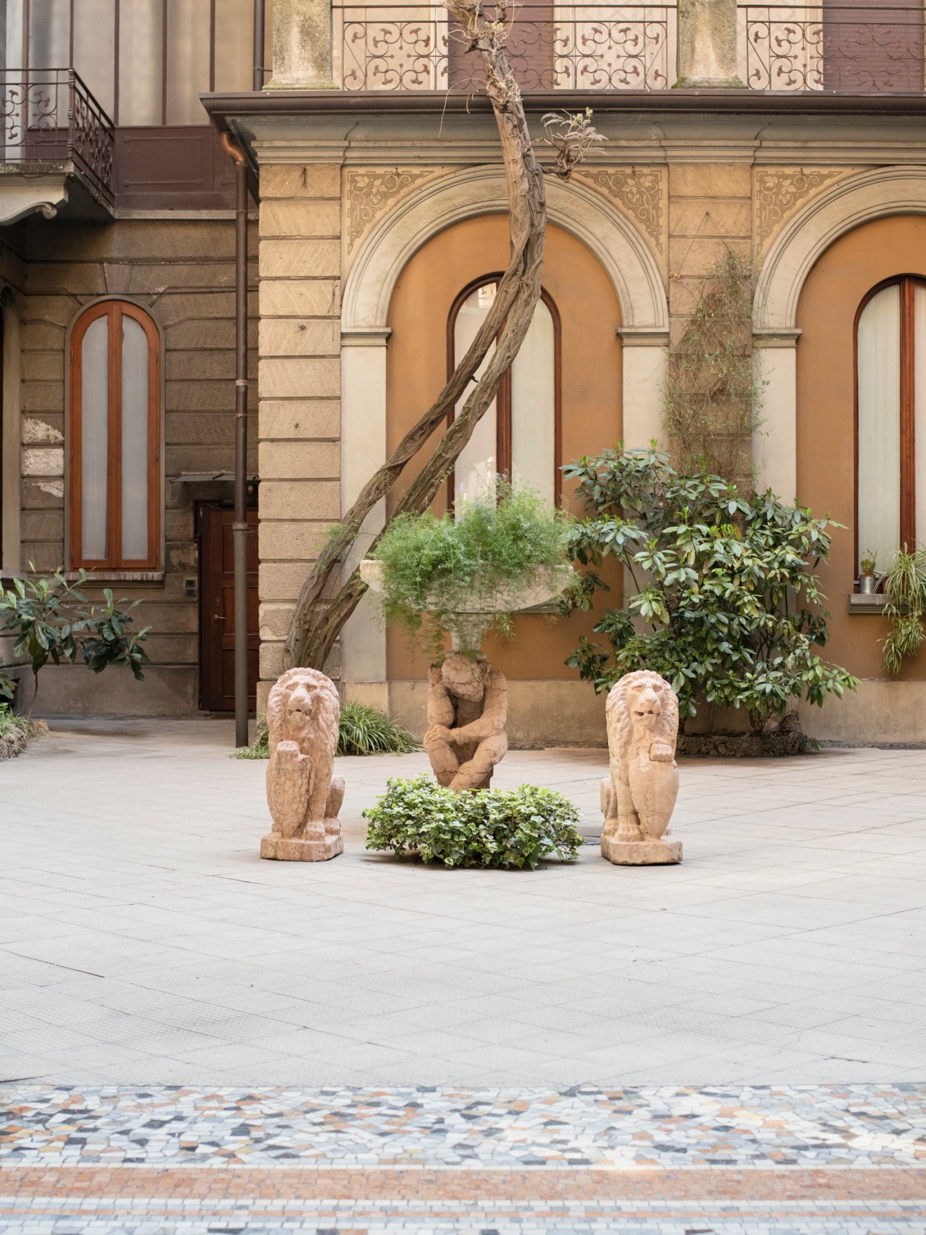 Courtyard of Milanese palazzo with classical stone lion sculptures, ornate arched architecture and decorative balconies