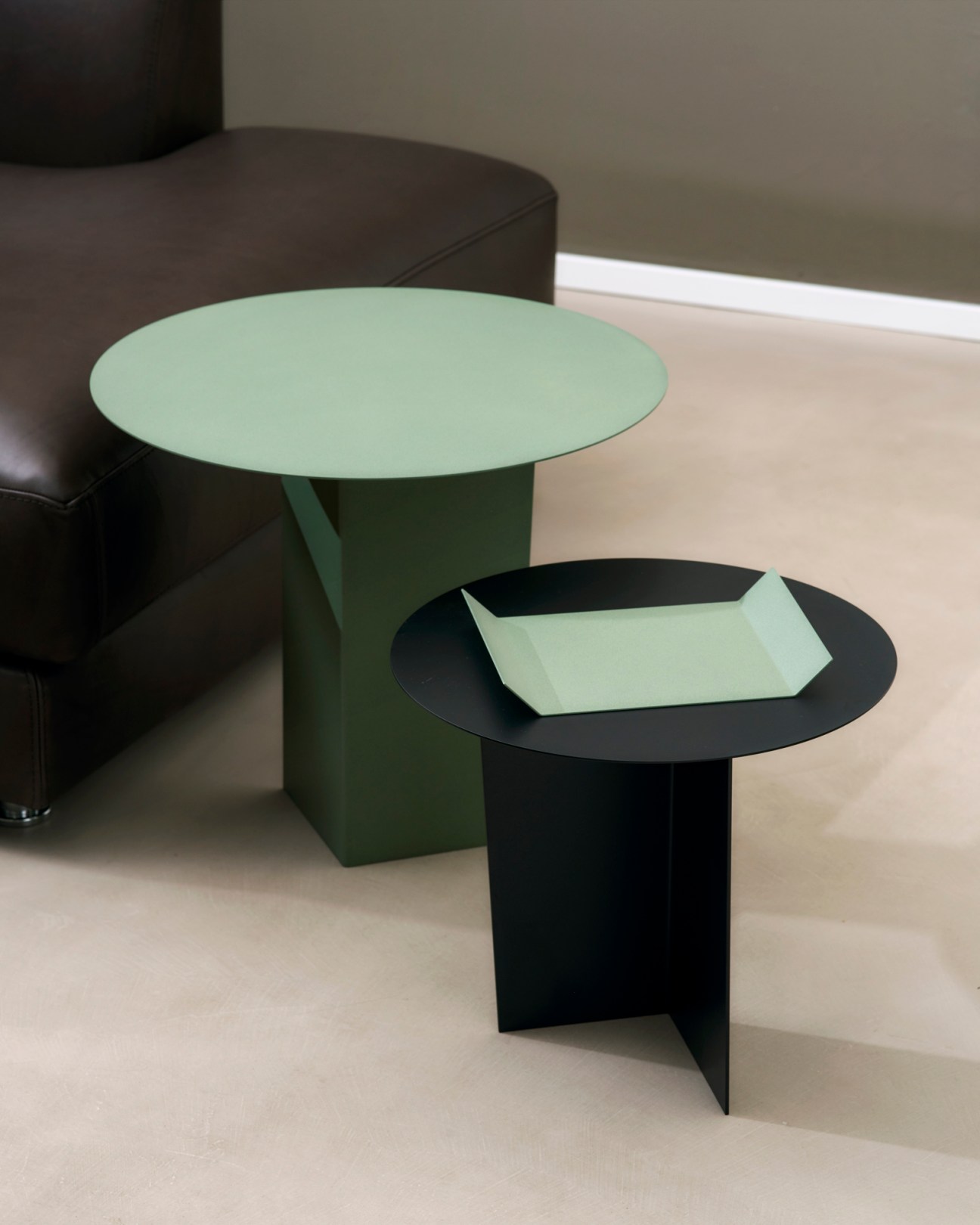 Green and black modern side tables with geometric bases and circular tops, featuring minimalist angular design