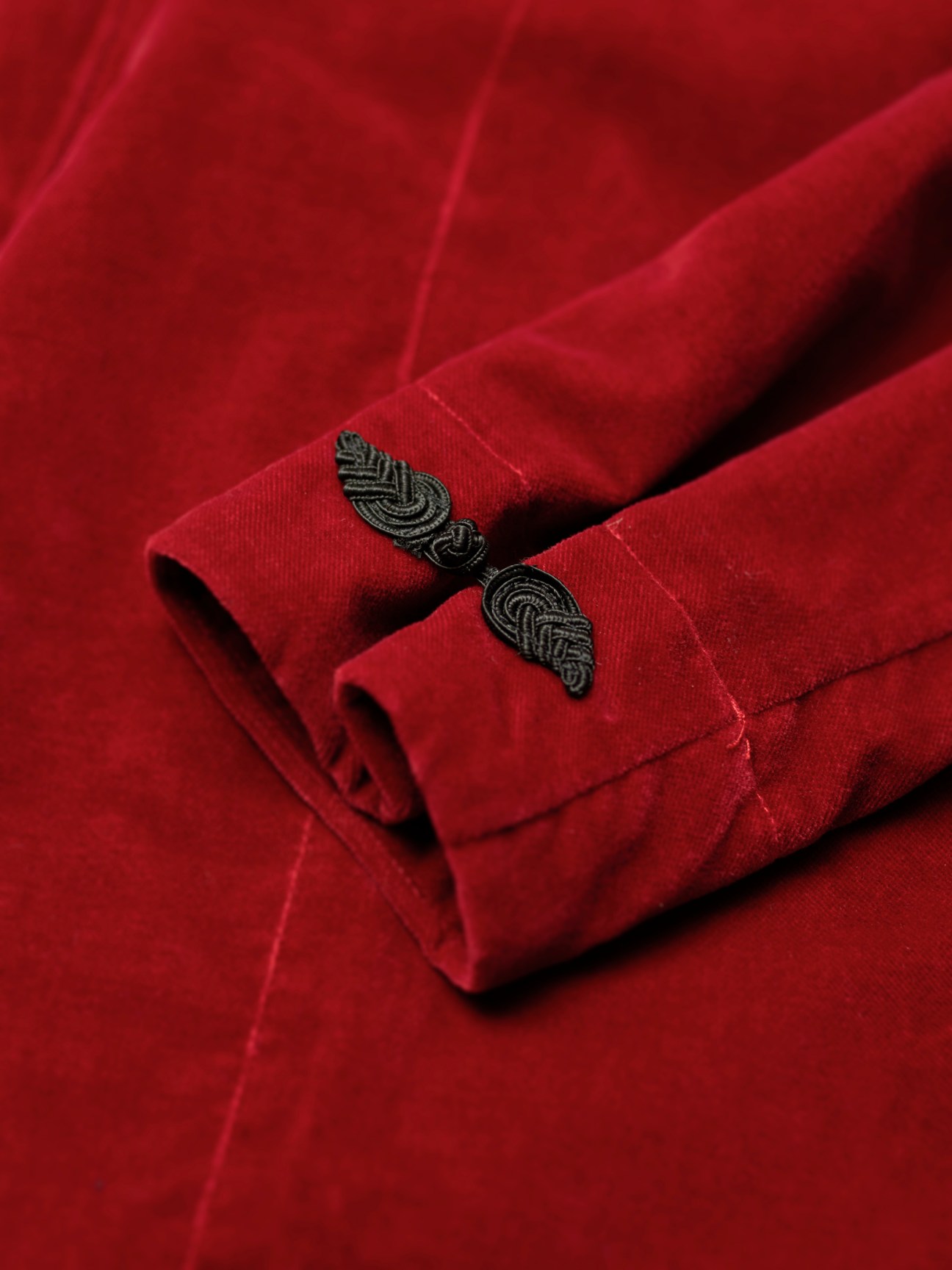 Close-up of red fabric with decorative embroidered leaf motifs on cuffs.