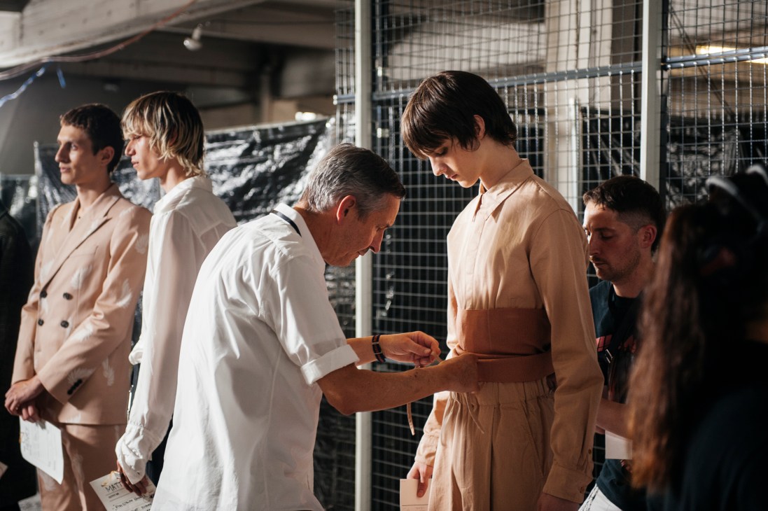Dries Van Noten styling and adjusting a garment on a male model backstage at his Paris menswear show