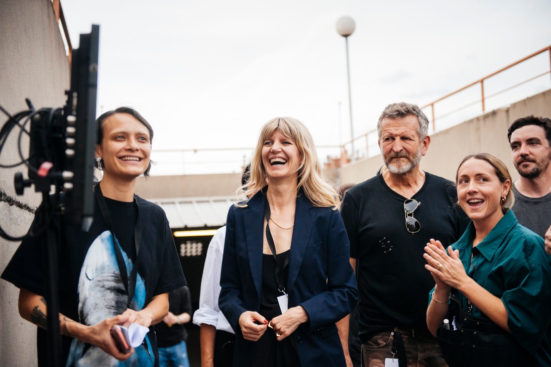 Dries Van Noten design and production team members standing together outdoors smiling and laughing in casual and business attire