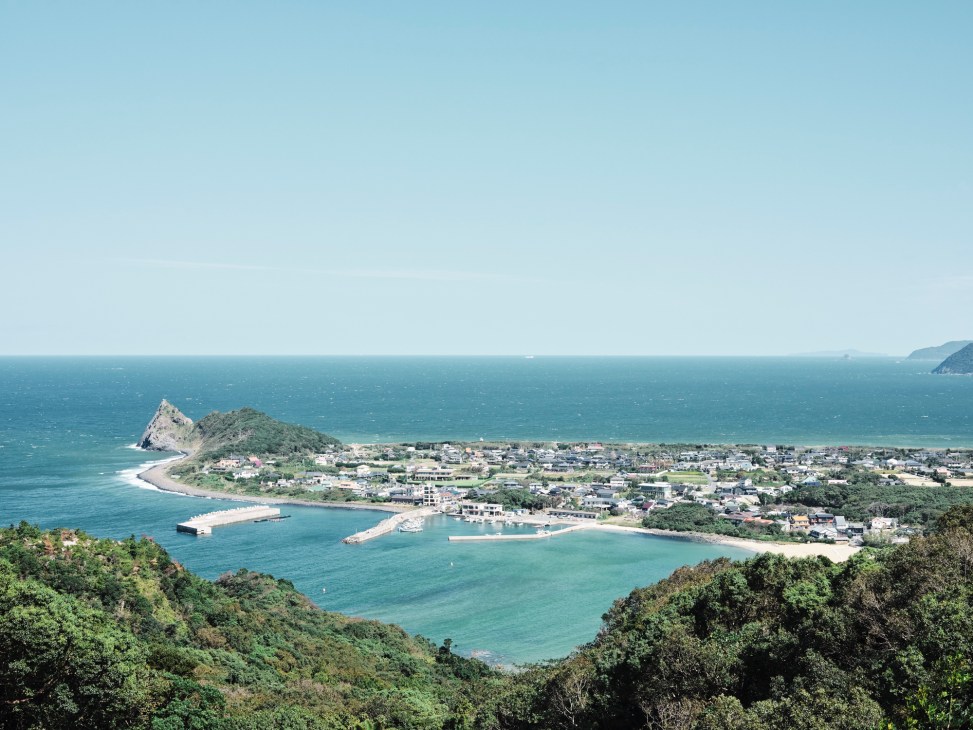 Aerial view of Itoshima peninsula with turquoise waters, beaches, residential areas and forested hills.