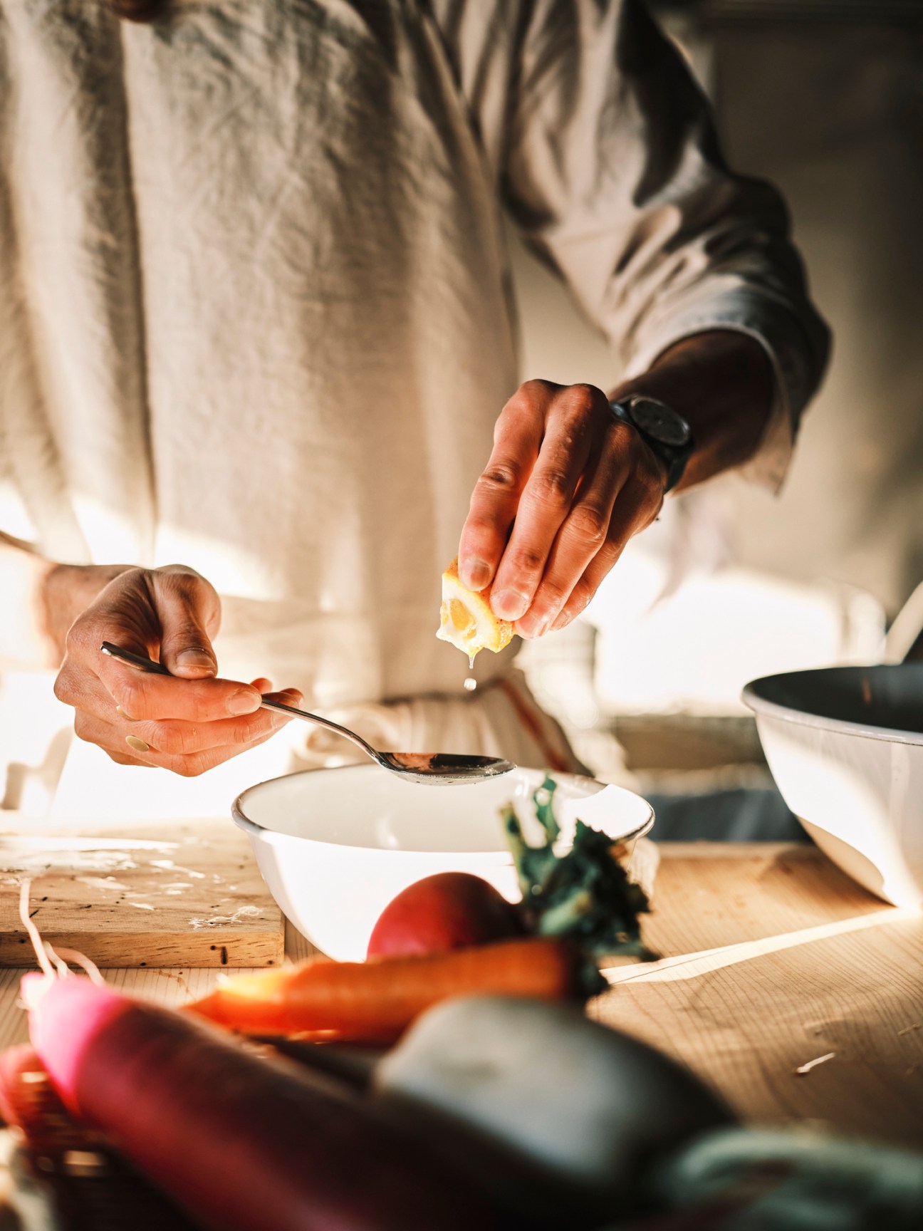 Chef Shinichiro Harakawa preparing food at counter in small restaurant kitchen, squeezing lemon over spoon