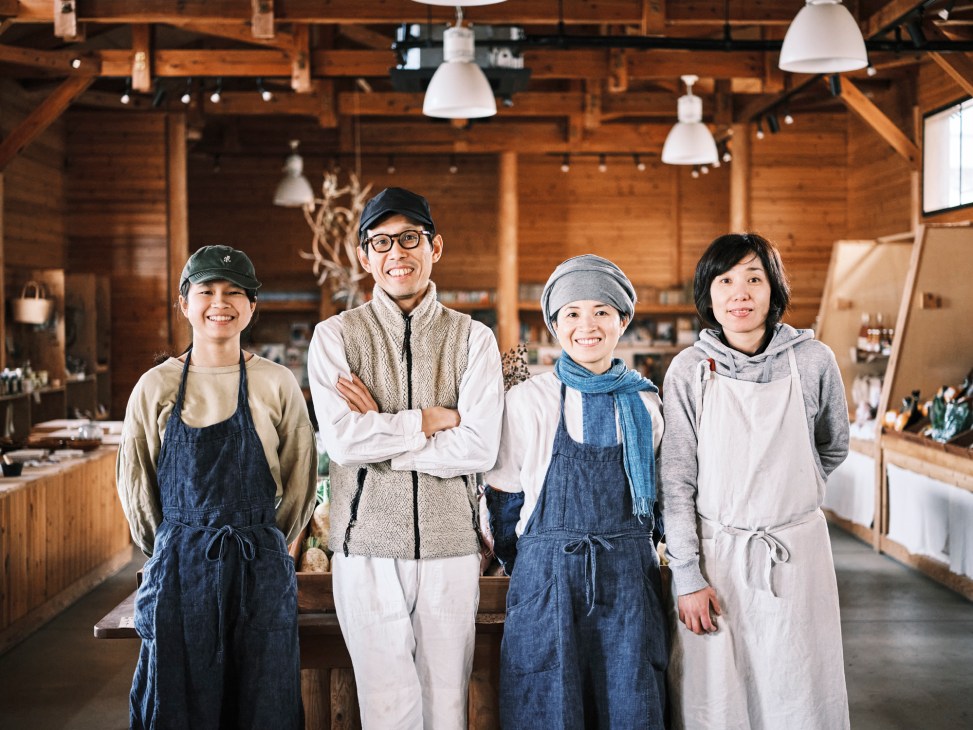 Four people standing together in a rustic wooden interior restaurant space with pendant lights