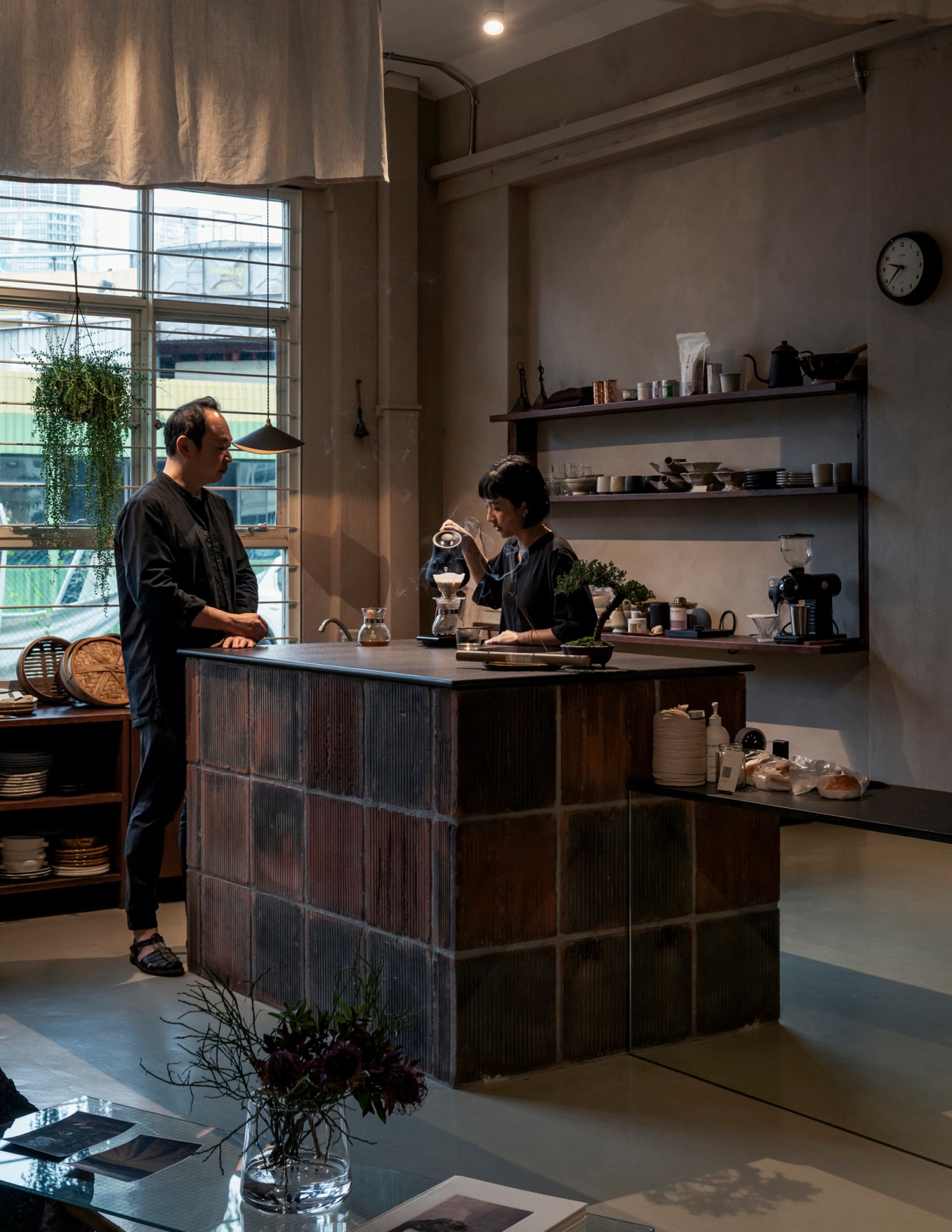 Interior of Asaru Studio showing two people in a minimalist space with shelving, pottery, and natural materials