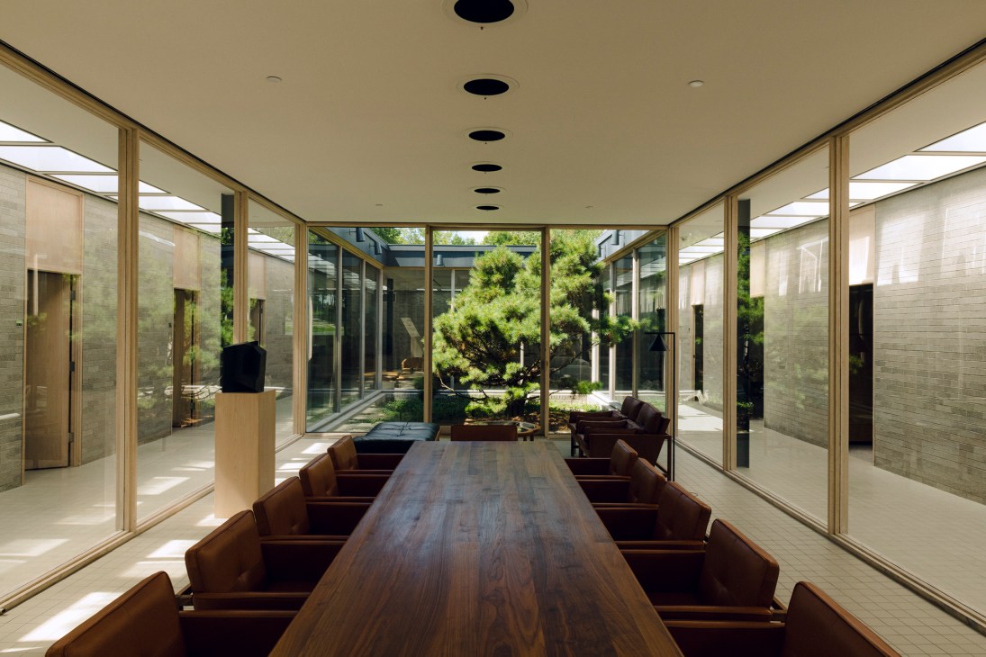 Modern office interior with glass meeting room, skylights, and private offices along perimeter walls