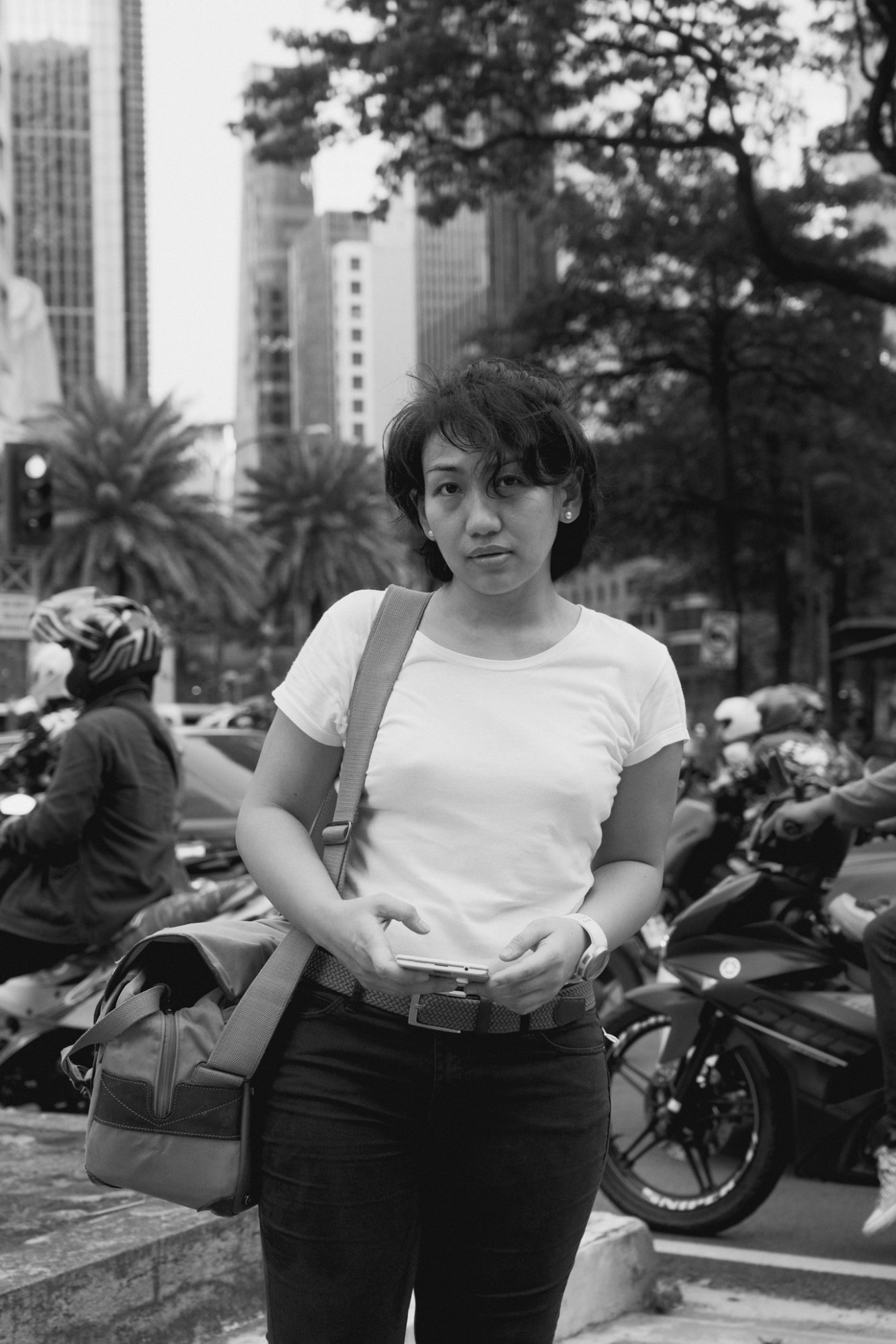 Aie Balagtas See, a Filipino crime reporter, sits outdoors in an urban setting wearing a white t-shirt
