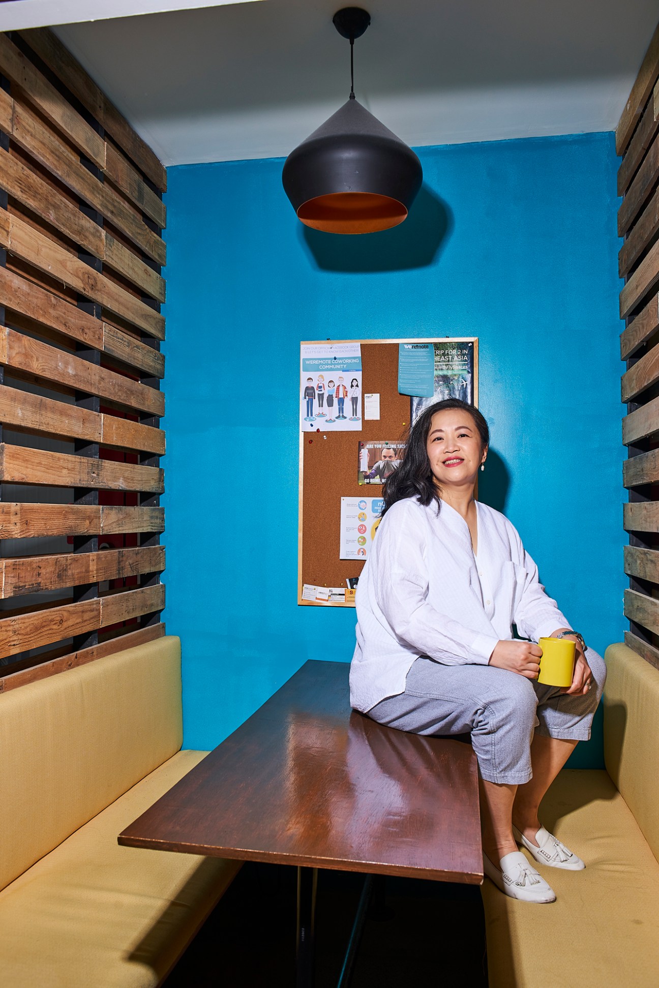 Eileen Borromeo, co-founder of Podcast Network Asia, sitting in a casual office space holding a yellow mug