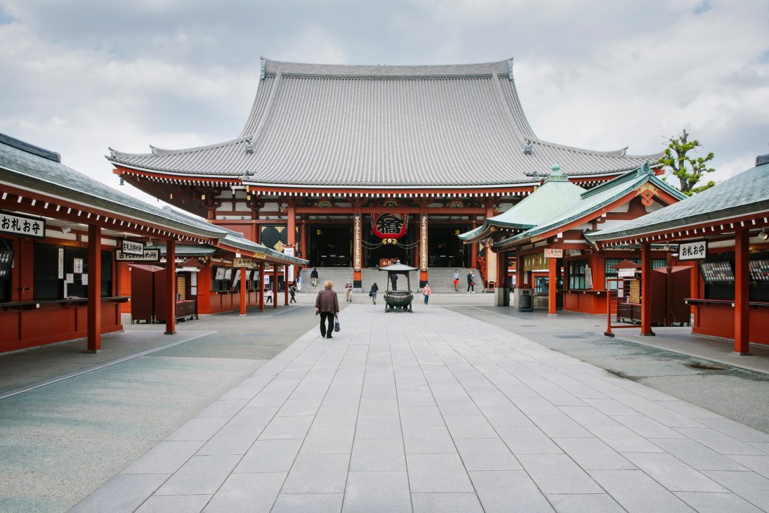 Empty Asakusa temple square in Tokyo during pandemic lockdown with traditional red structures and few visitors.