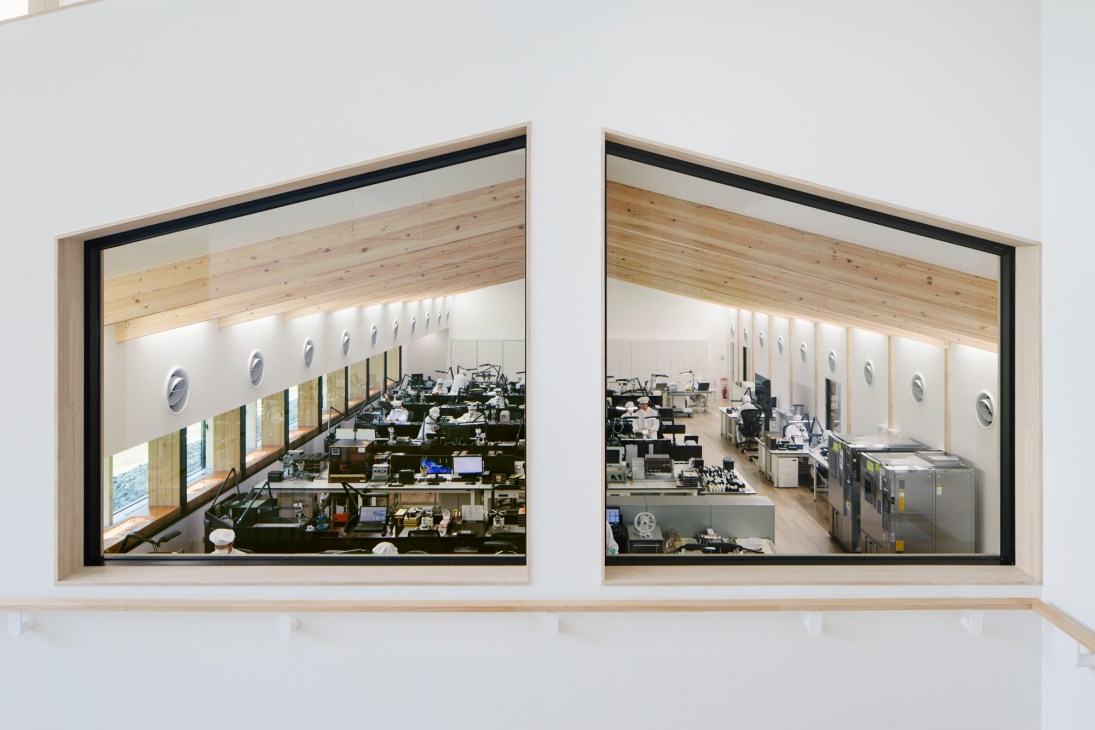 Two large windows showing view into Grand Seiko's clean room assembly area with workstations and equipment