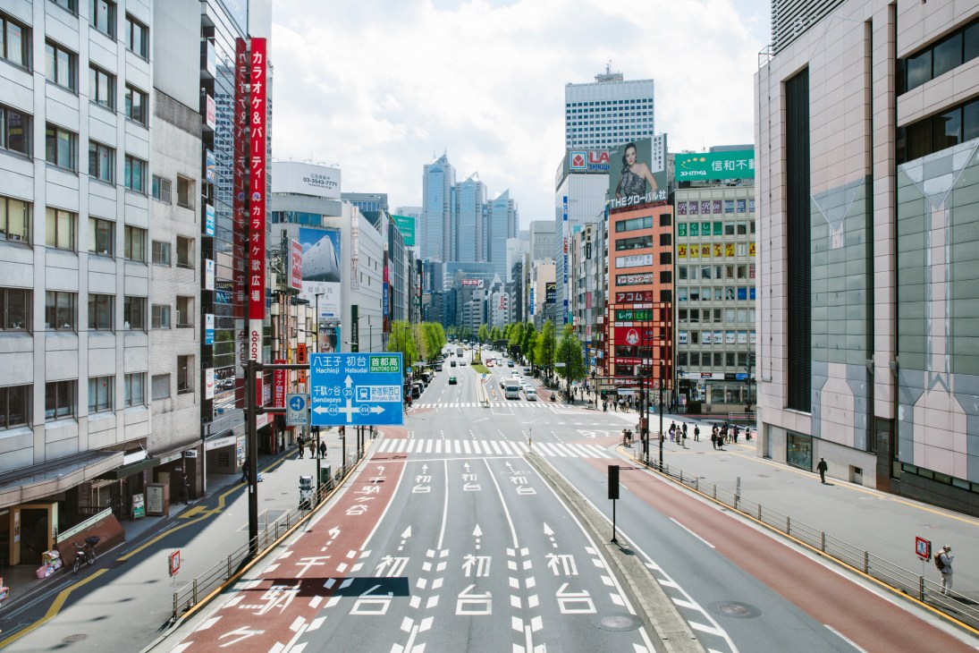 Empty Tokyo street intersection with Japanese signage, buildings, and clear crosswalks during pandemic lockdown.