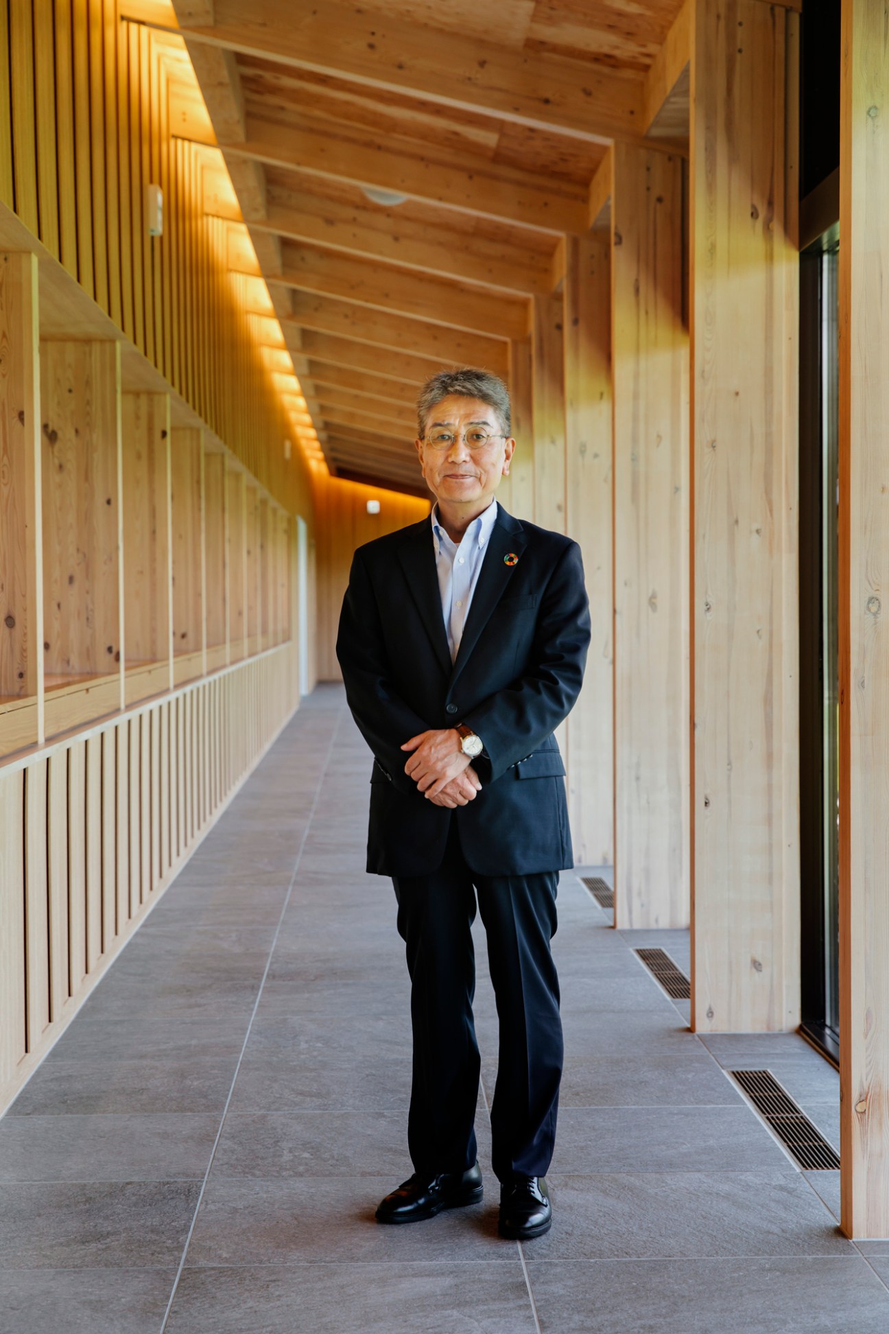 Yoshiaki Hayashi, president of Morioka Seiko Instruments, standing in a wooden corridor