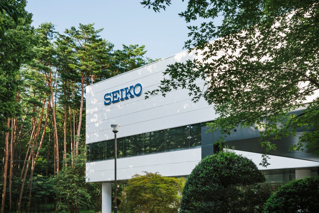 Modern white building with SEIKO signage surrounded by lush green trees and landscaping