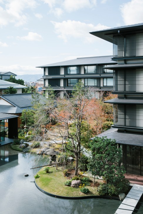 Traditional Japanese garden with pond, trees, and wooden walkways at Hotel The Mitsui Kyoto