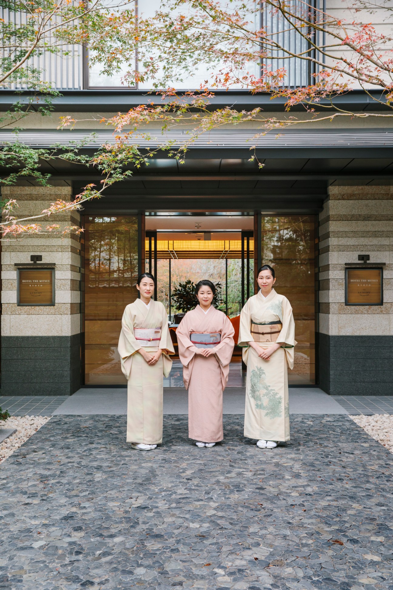 Three women in traditional Japanese kimono standing in front of Hotel The Mitsui Kyoto entrance