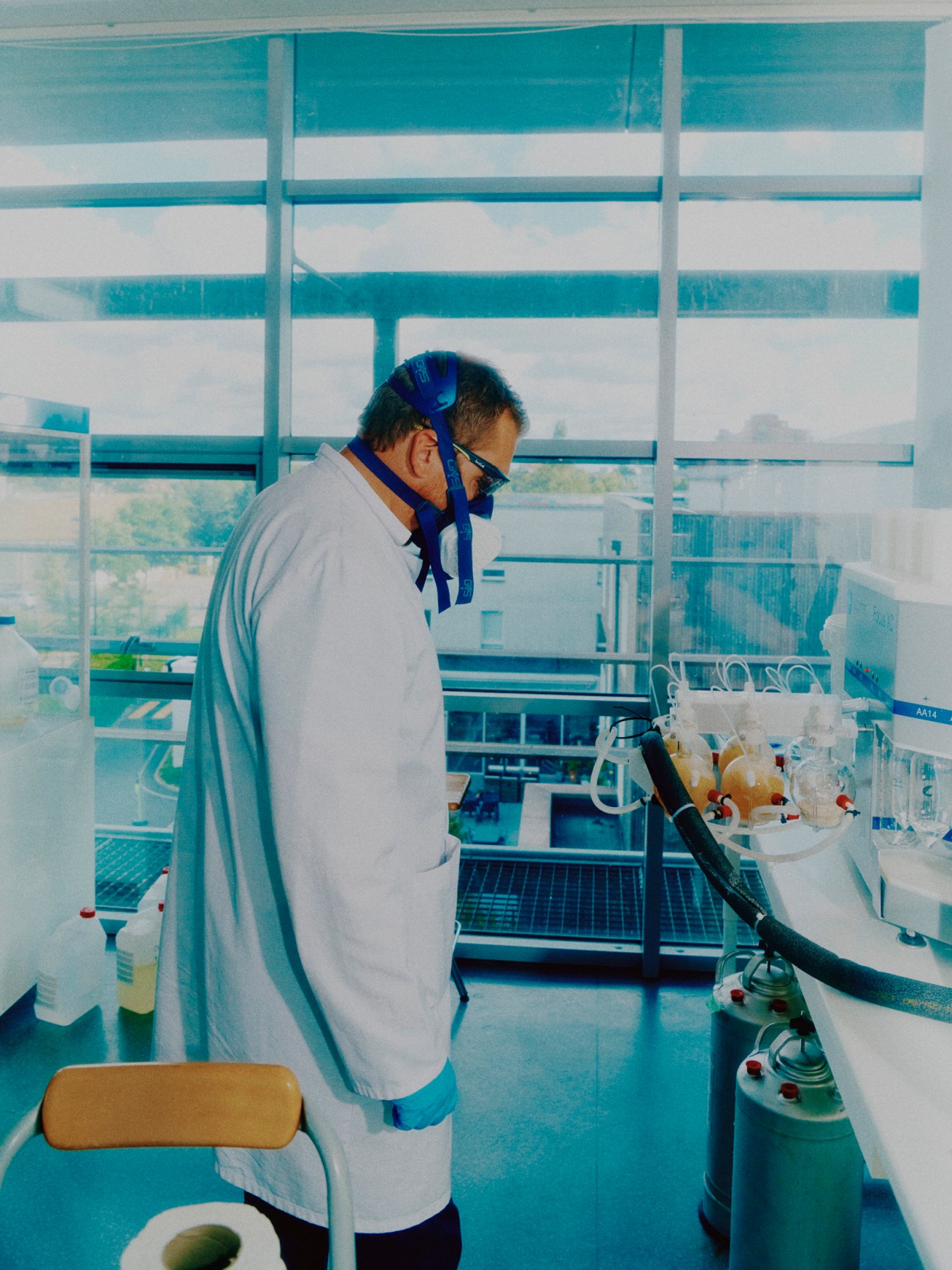 Scientist in white lab coat and protective mask working at laboratory bench with equipment and supplies
