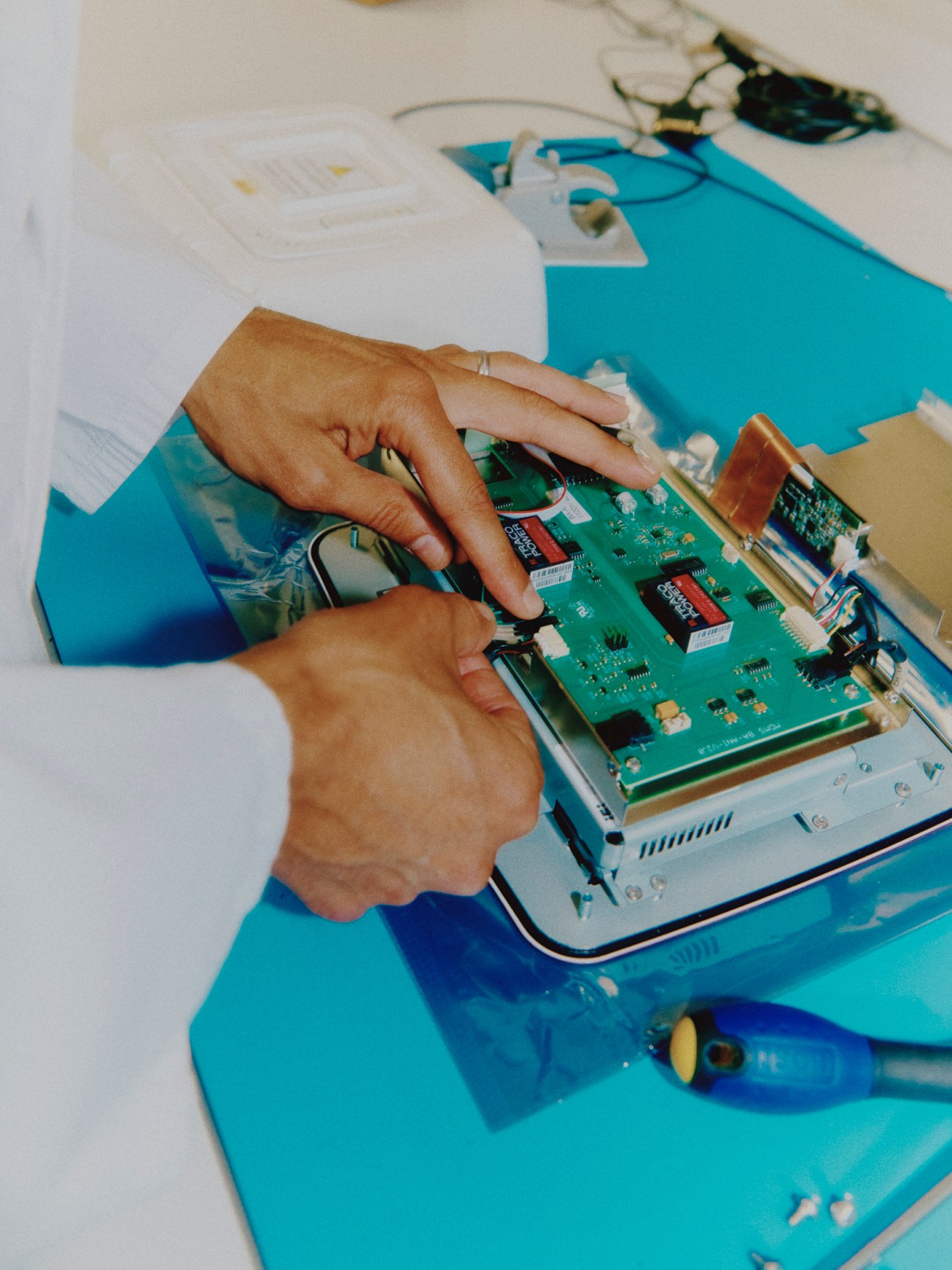 Hands assembling electronic circuit board components for MDoloris medical monitoring device