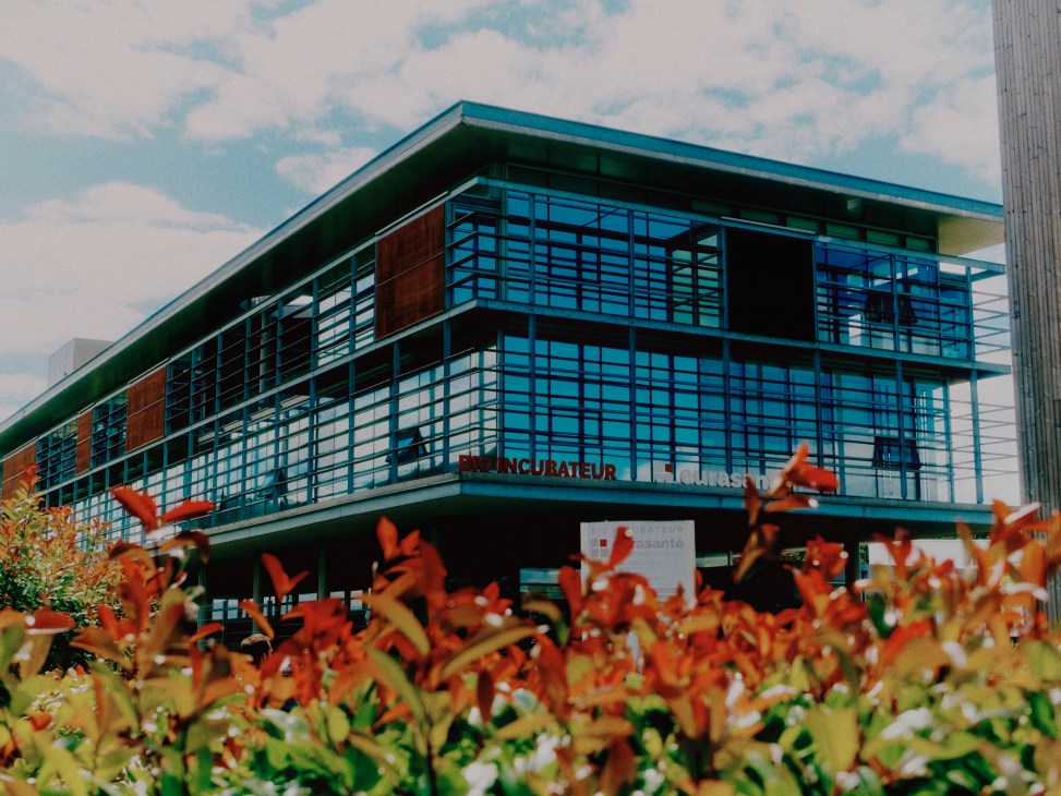 Modern glass and brick bio-incubator building with large windows surrounded by autumn foliage