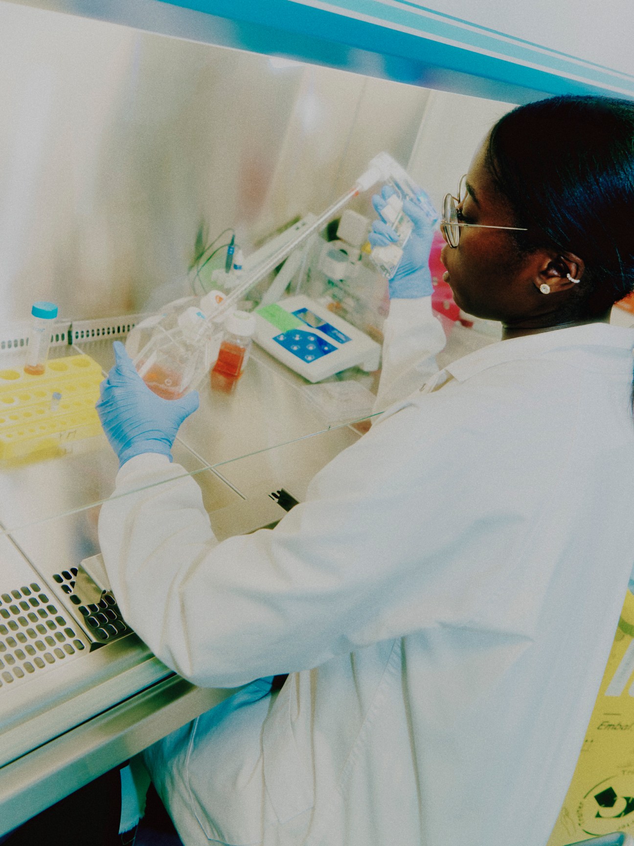 Laboratory technician in white coat and blue gloves working with samples in sterile research environment