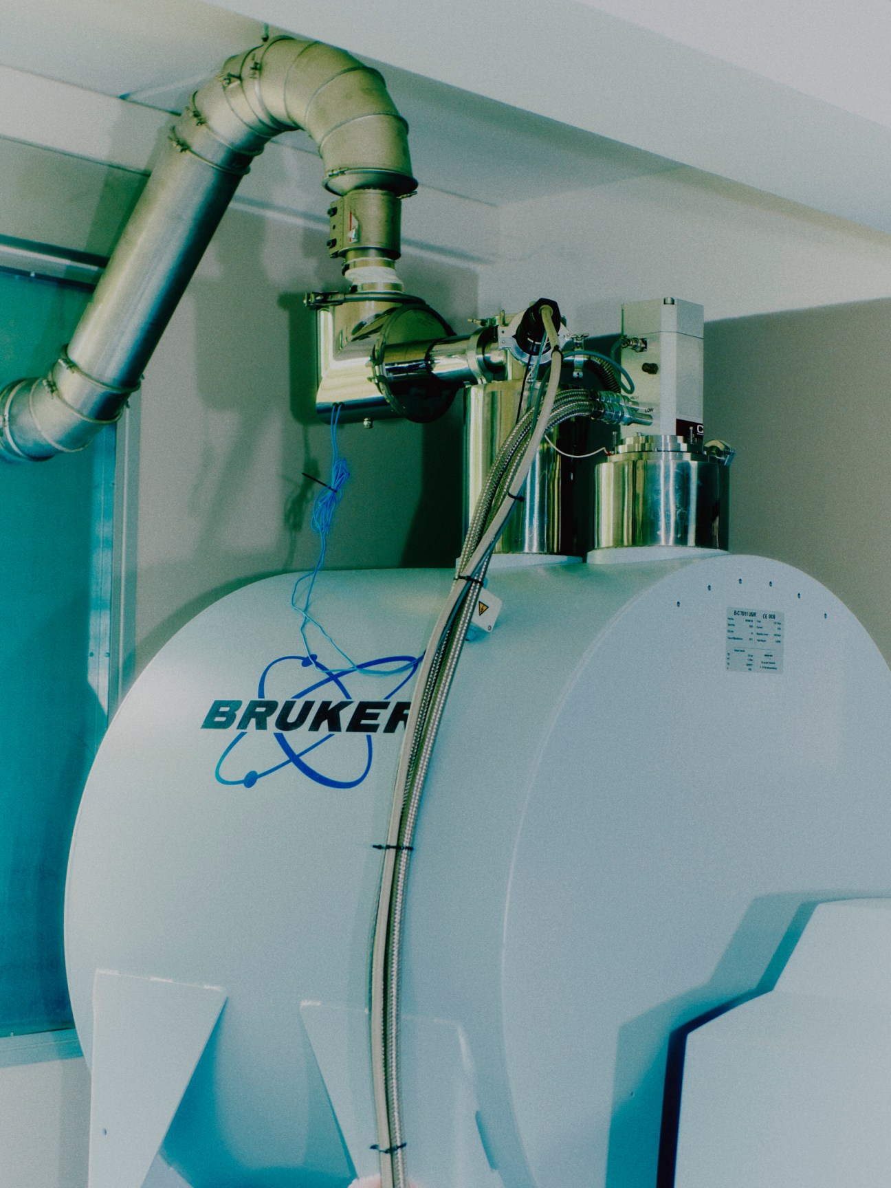 Large white Bruker scientific research equipment with metal ducting and cables in laboratory setting