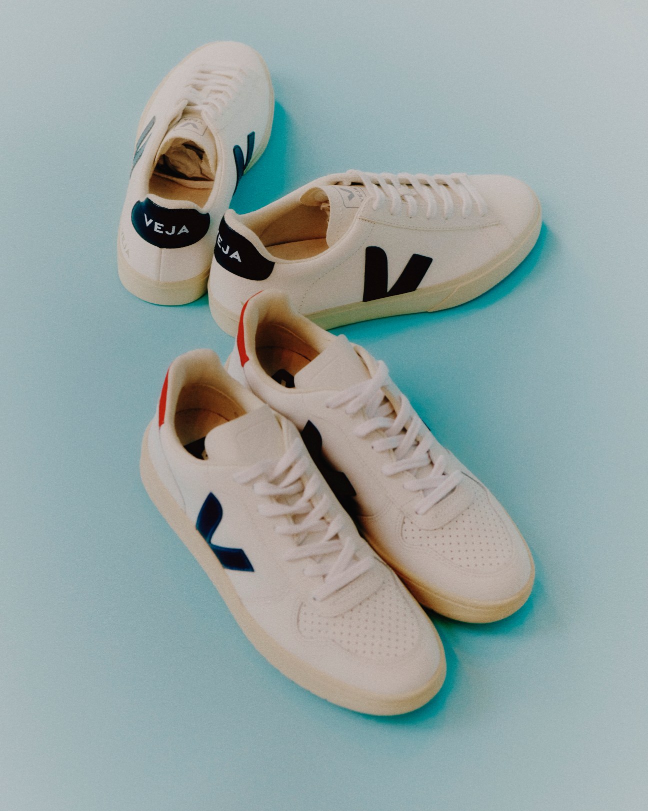 Multiple white Veja trainers arranged on a surface showing various color combinations of the V logo