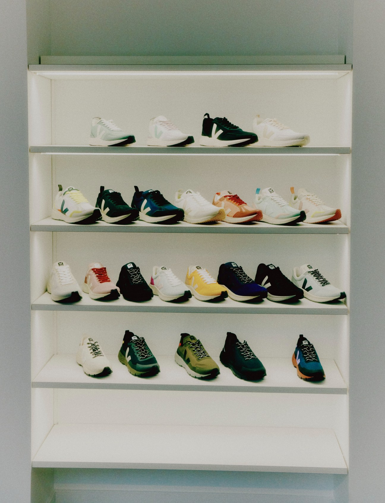Display of colorful Veja sneakers arranged on white shelves in retail setting