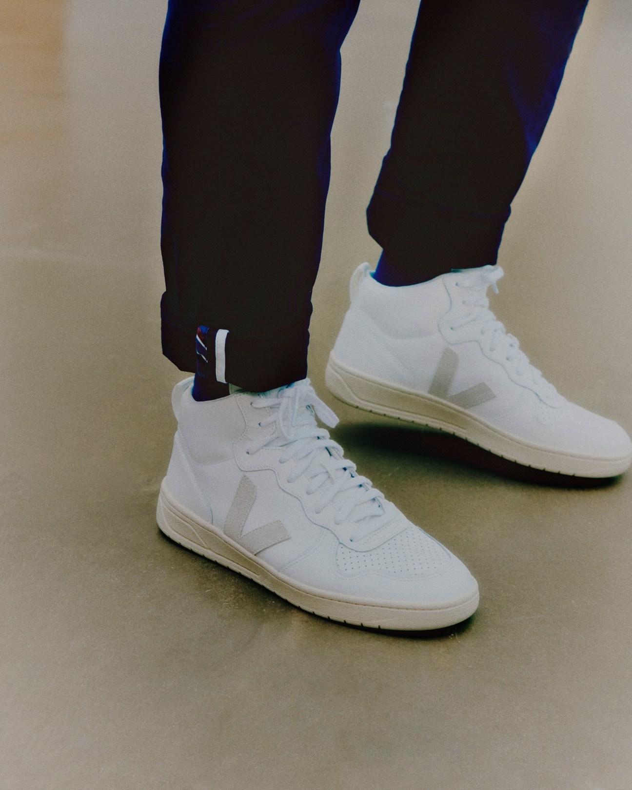 Person wearing white Veja sneakers with distinctive V logo and dark pants