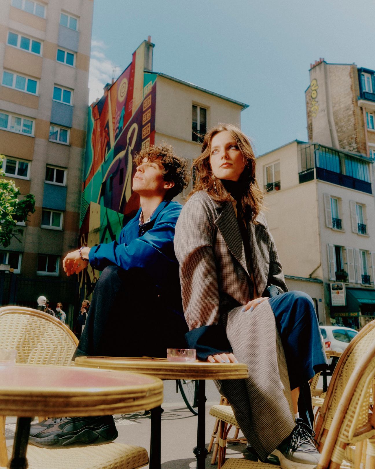 Two people sitting outdoors at a cafe table, both looking upward