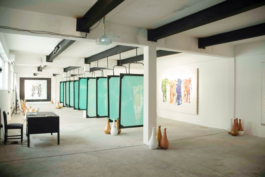 Interior view of Institute Museum with turquoise panels, artworks on white walls, and sculptural vessels on the floor.