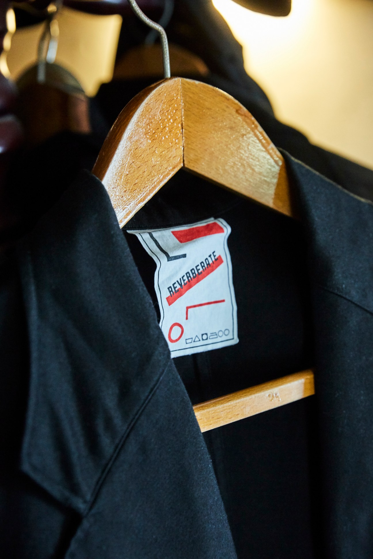 Reverberate menswear jacket with wooden hanger and designer label detail.