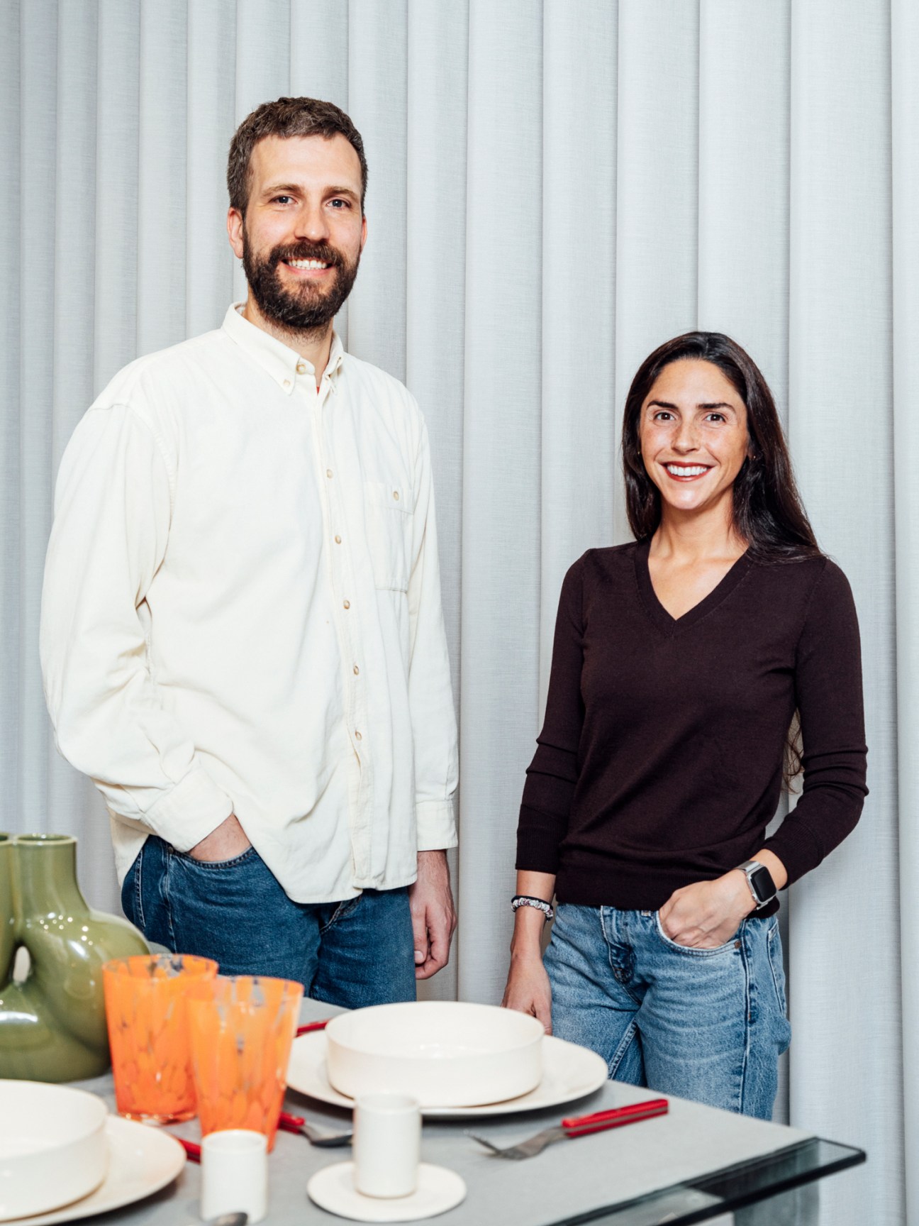Man and woman standing together smiling in indoor setting with white vertical paneled wall