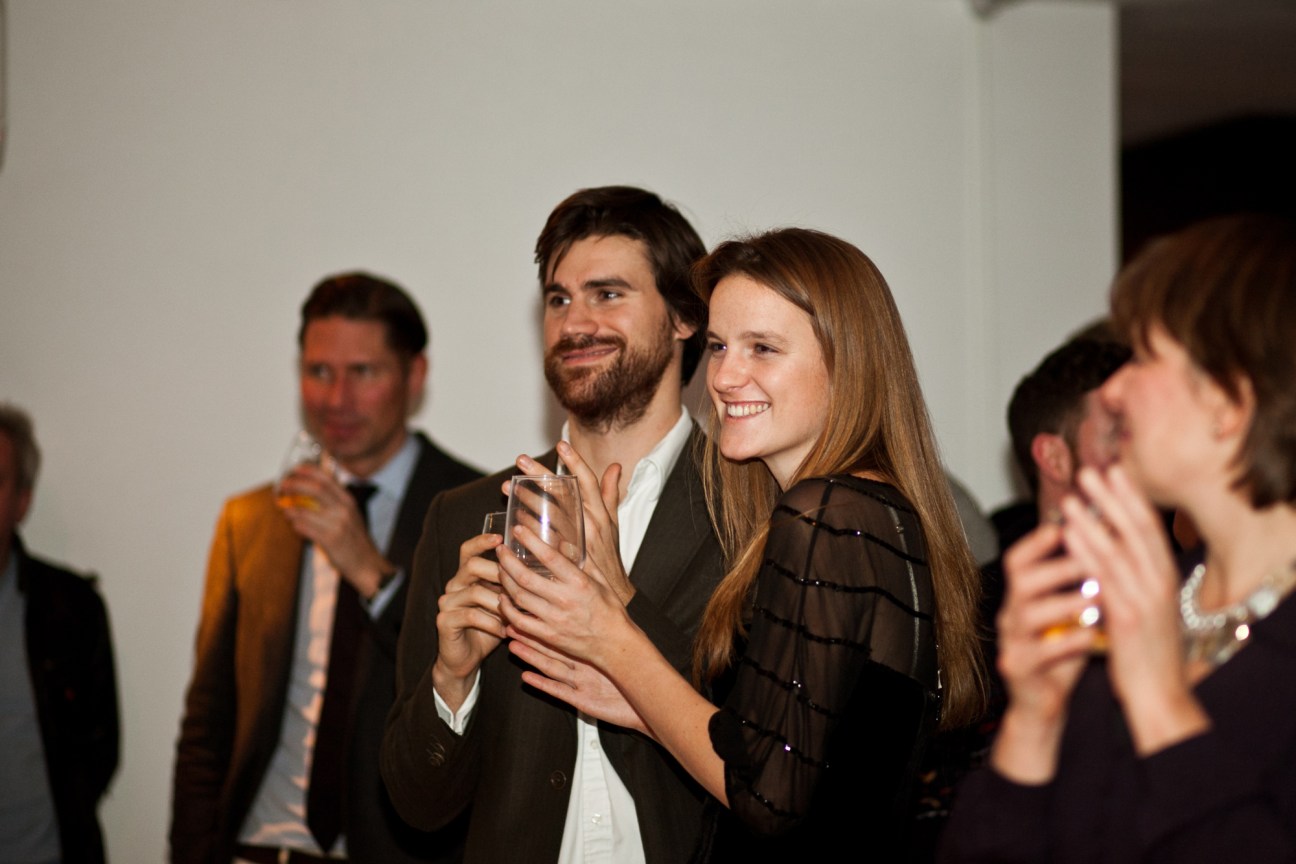 A man and woman holding drinks and smiling at what appears to be a social gathering or party