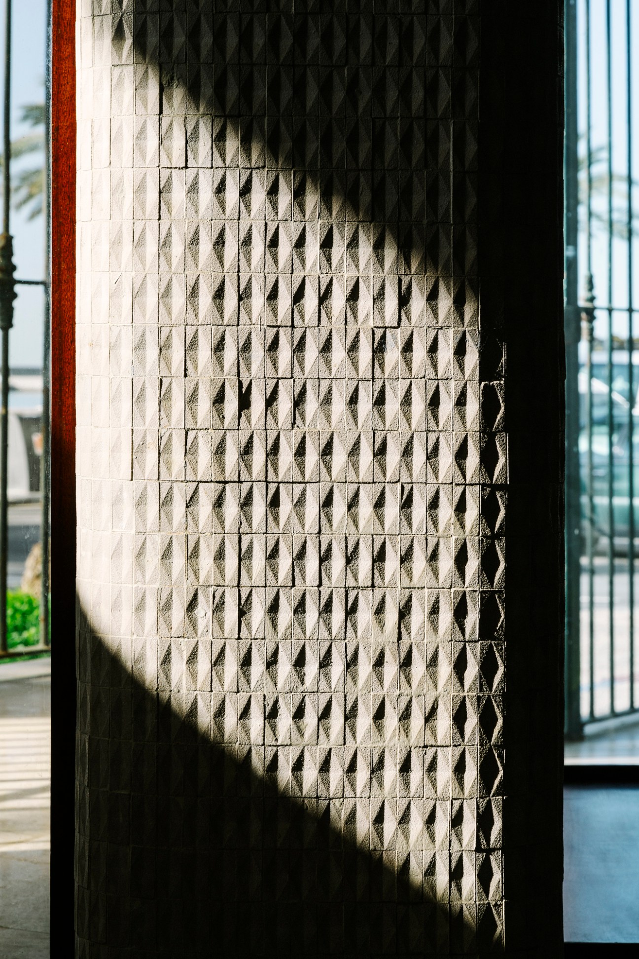 Sunlight casts shadows on textured ceramic tiles covering an interior wall at Melilla 31.
