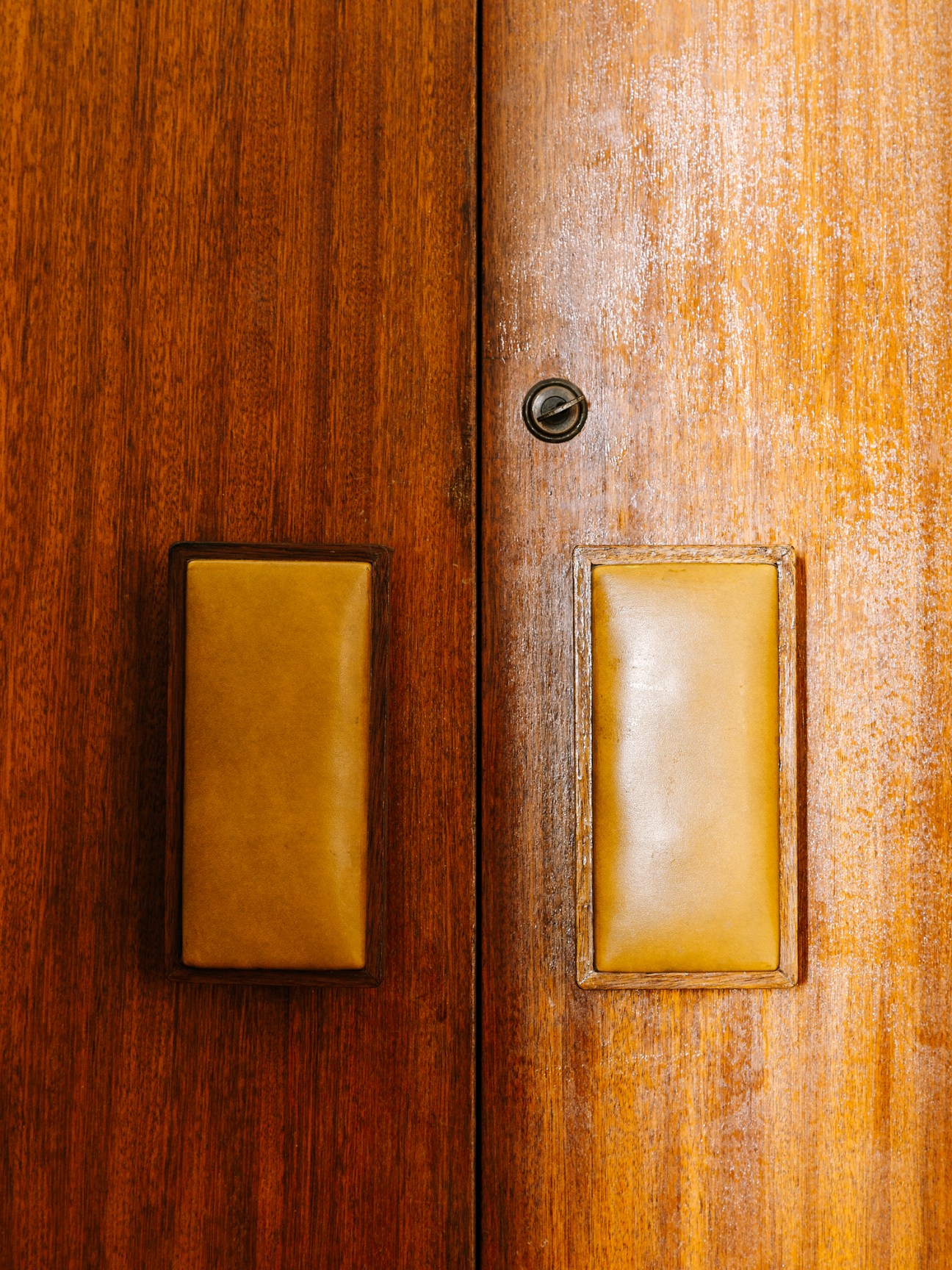 Two wooden door panels with yellow-toned leather cushioned panels and metal fixtures.
