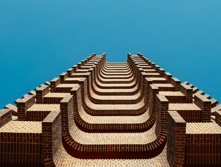 Torre Ripalda's distinctive curved brick facade with repeating horizontal bands photographed from below against blue sky