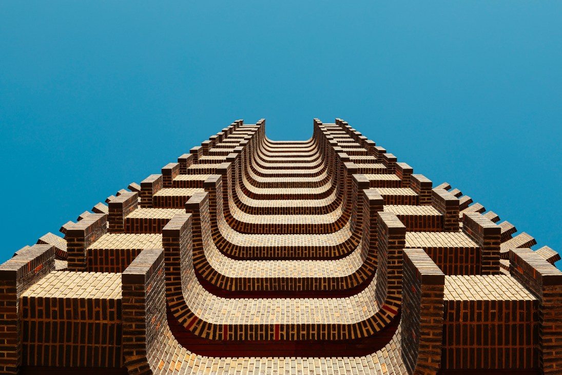 Torre Ripalda's distinctive curved brick facade with repeating horizontal bands photographed from below against blue sky