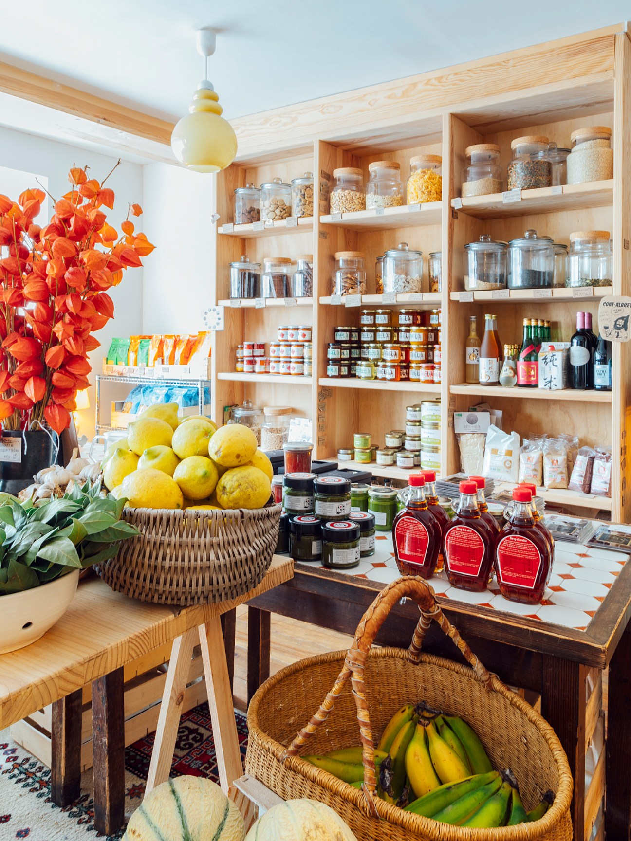 Interior of Yaoya shop with wooden shelves stocked with glass jars, bottles, and packaged goods.