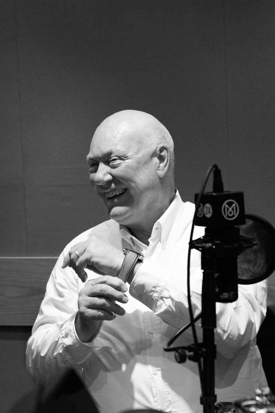 Jean-Claude Biver smiling while holding a piece of film strip in a black and white photograph
