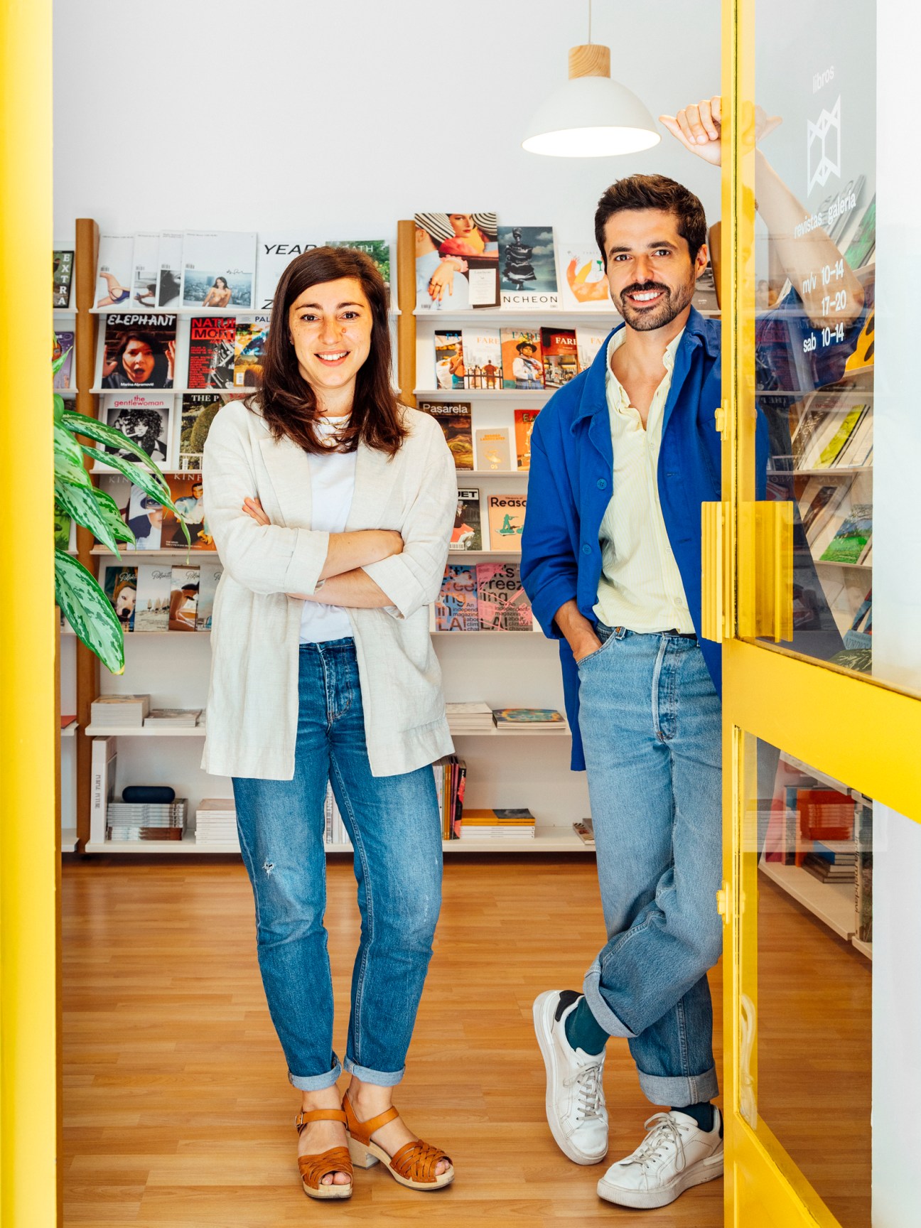 Man in blue jacket standing next to yellow shelving in bookstore with magazines displayed