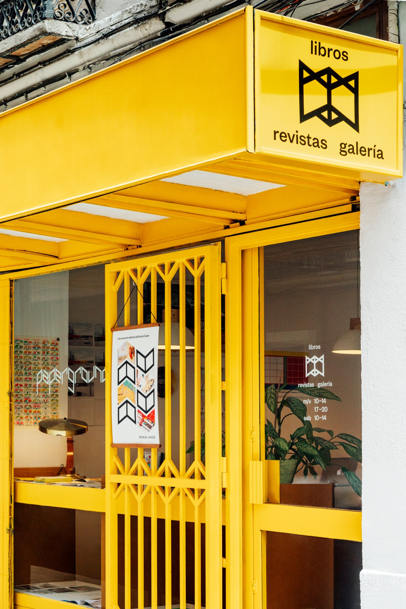 A bright yellow storefront with geometric signage for a bookstore and gallery.