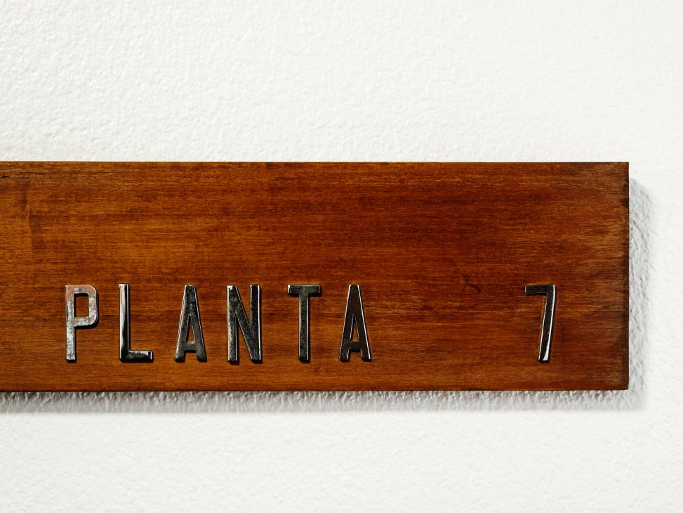 Wooden sign reading 'PLANTA 7' mounted on wood grain surface