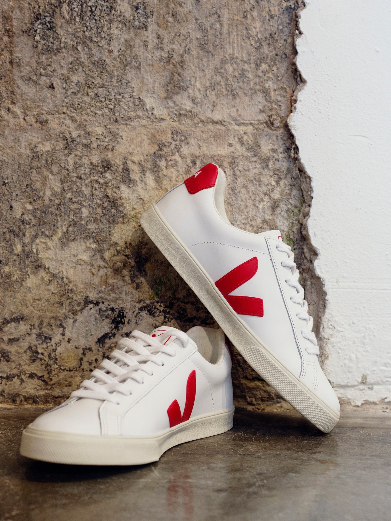 White sneakers with red V logo displayed on wooden surface