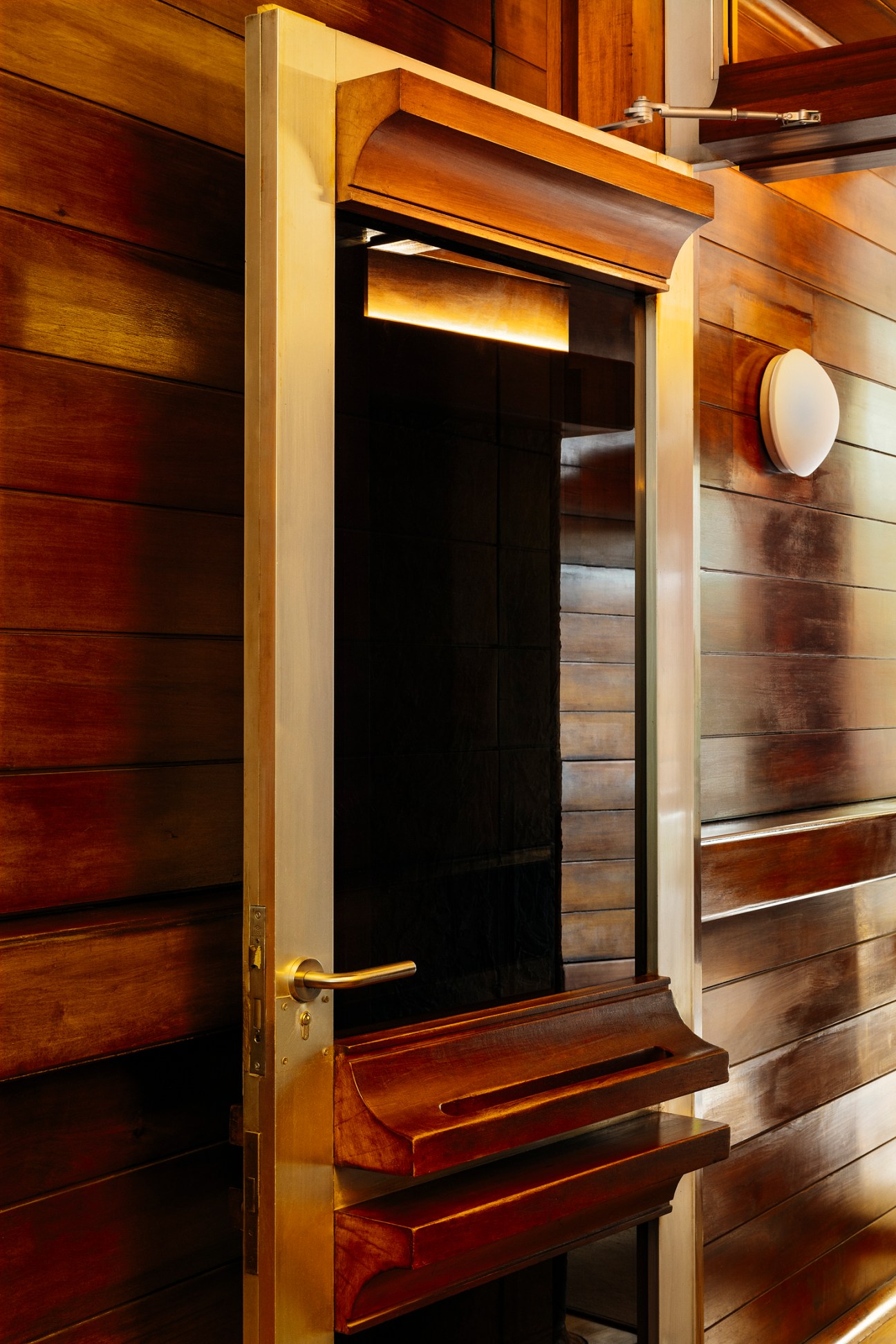 Original curved wooden apartment door with brass handle reflecting the building's architectural vernacular