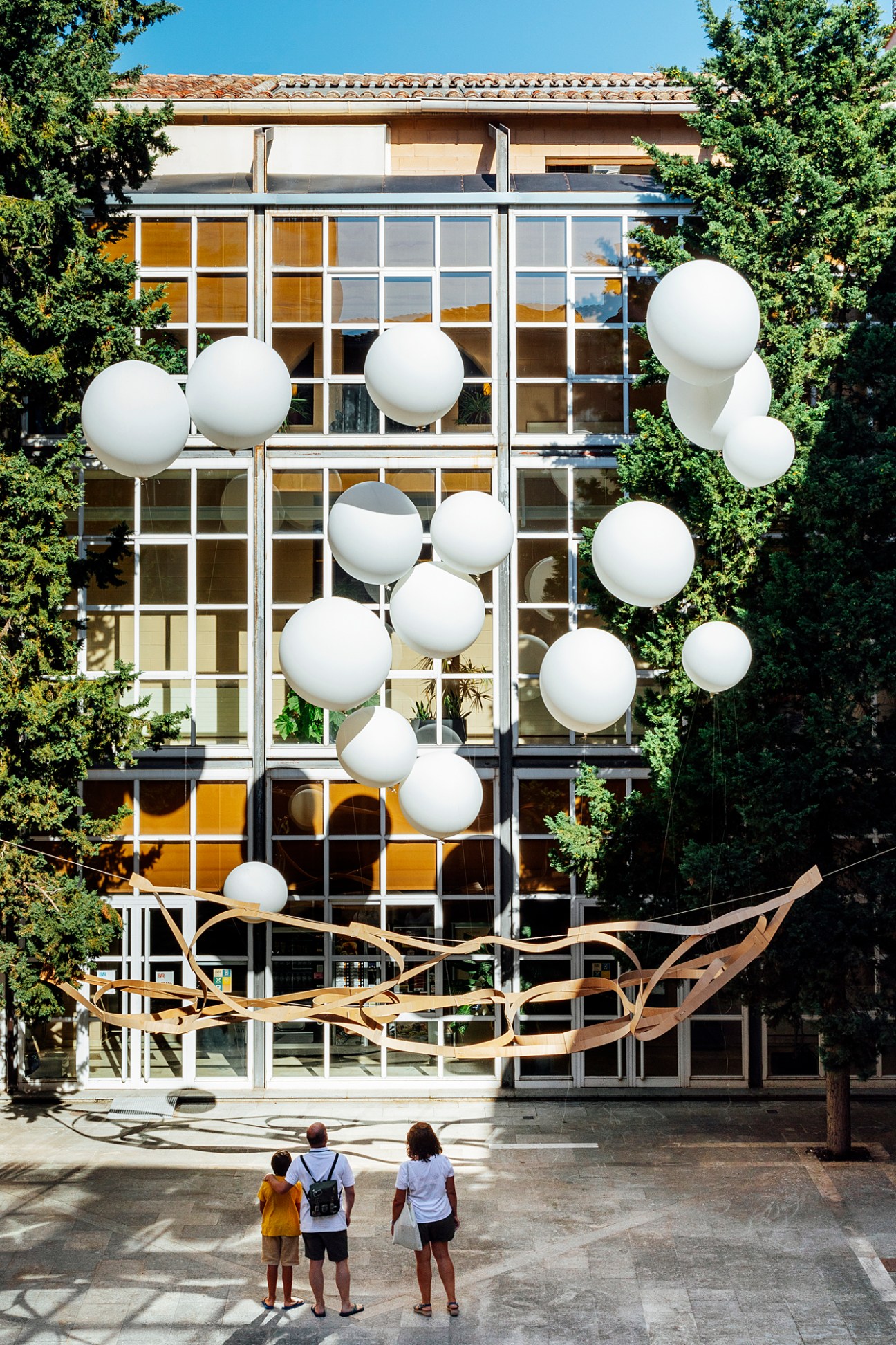 Installation by the Toledo School of Architecture featuring white spherical balloons and curved wooden ribbons