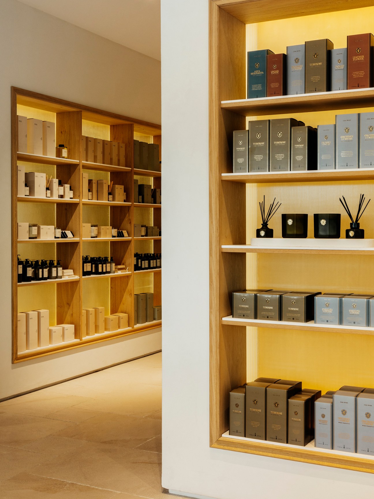 Warm wooden shelving displays luxury home goods including candles, diffusers and boxed products in organized rows