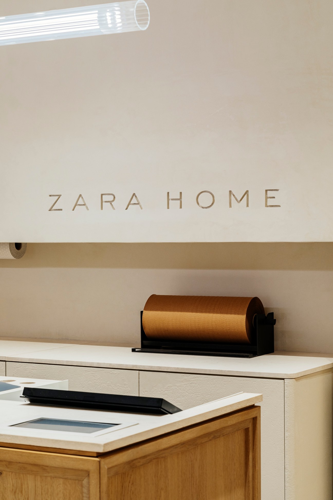 Modern retail counter with wooden paper roll dispenser and minimalist design elements in neutral tones